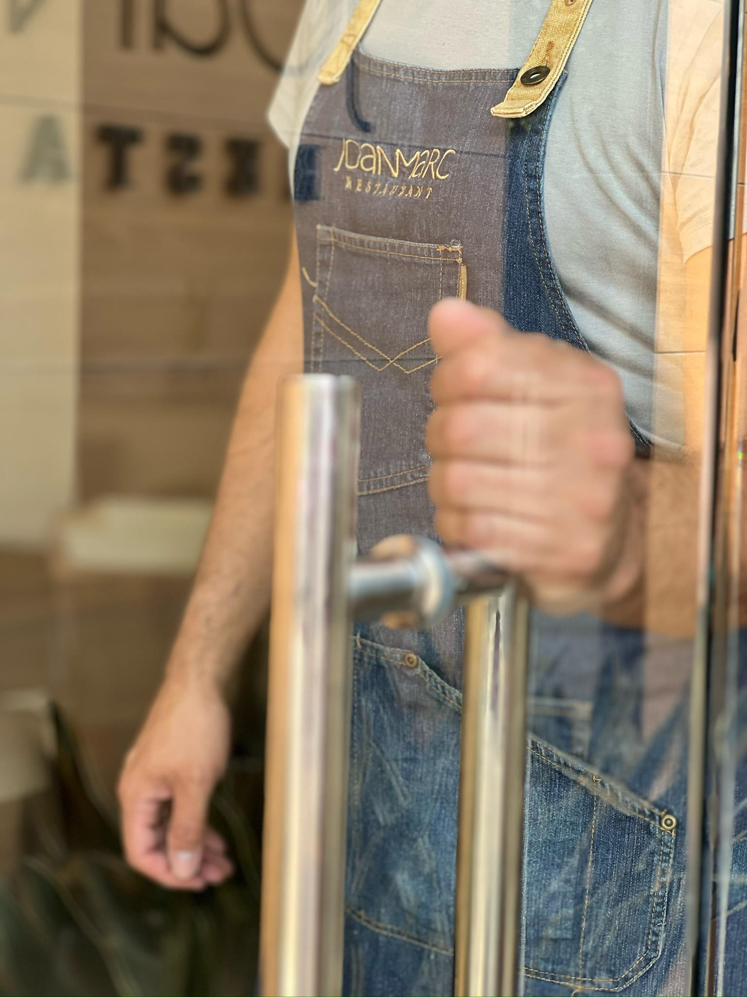 El delantal de Joan Marc y la mano en el tirador, a punto de abrir la puerta