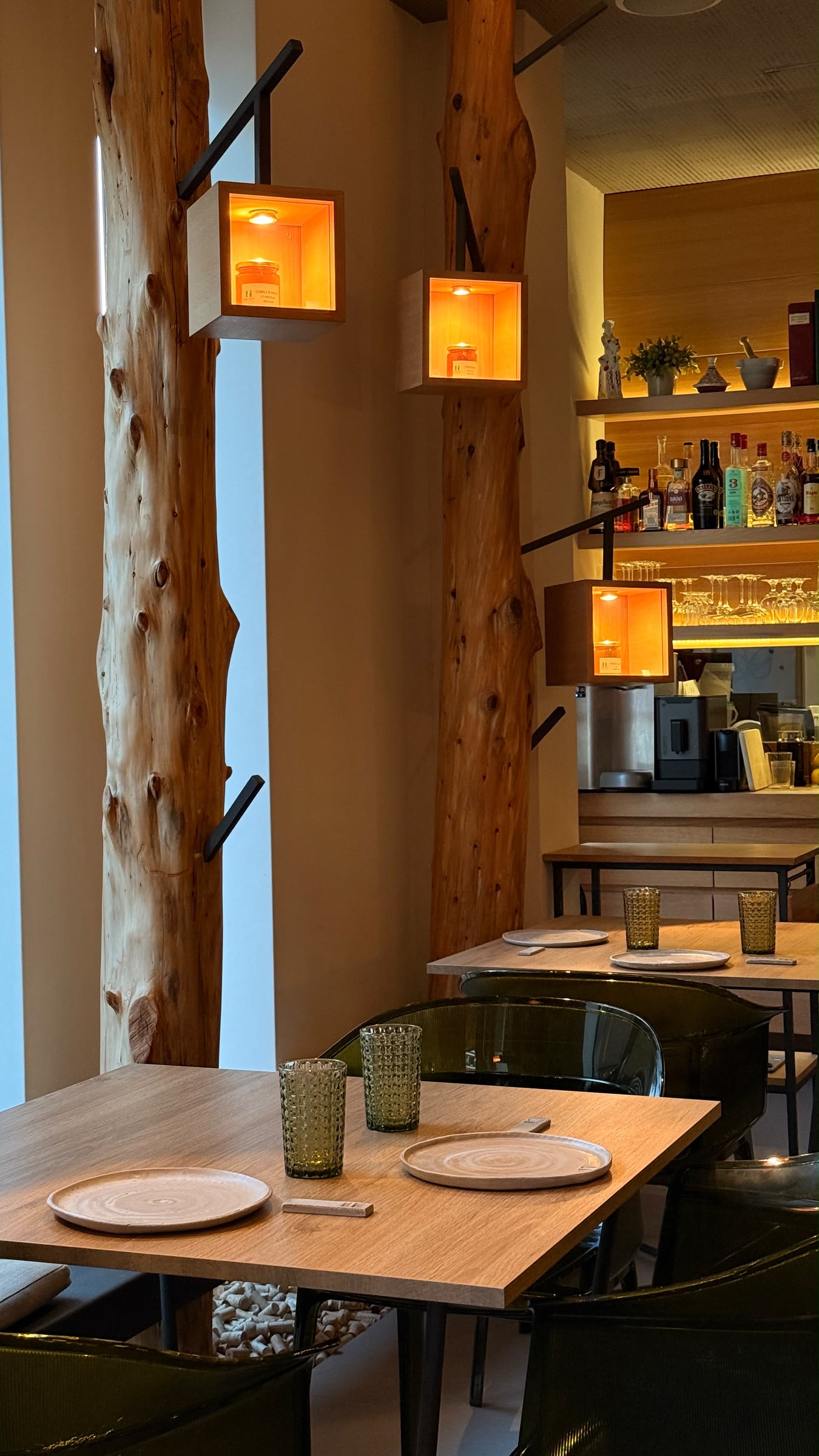 Troncos de madera con luces cálidas y mesas puestas en el comedor